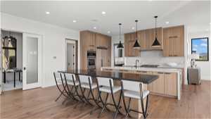 Kitchen with tasteful backsplash, a center island, light hardwood / wood-style floors, pendant lighting, and stainless steel appliances