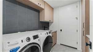 Laundry room with light tile flooring, sink, cabinets, and independent washer and dryer