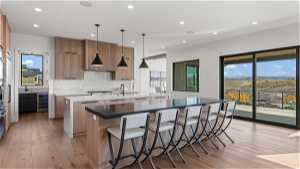 Kitchen with decorative light fixtures, a kitchen island, light hardwood / wood-style floors, and tasteful backsplash