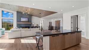 Kitchen with a breakfast bar area, light hardwood / wood-style floors, an island with sink, wood ceiling, and a fireplace