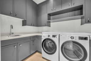 Washroom with sink, cabinets, and independent washer and dryer