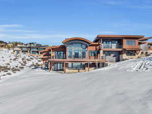 Snow covered back of property featuring a balcony