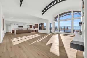 Unfurnished living room featuring a mountain view, high vaulted ceiling, and light hardwood / wood-style flooring