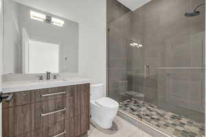 Bathroom with tile patterned flooring, vanity, a shower with shower door, and toilet