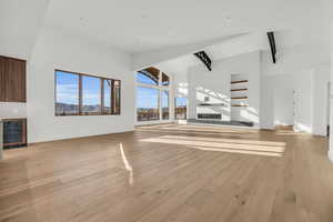 Unfurnished living room with wine cooler, a mountain view, high vaulted ceiling, and light wood-type flooring