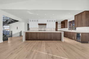 Kitchen with white cabinetry, decorative backsplash, light hardwood / wood-style flooring, and wine cooler