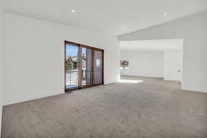 Carpeted spare room featuring vaulted ceiling