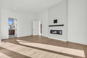 Unfurnished living room with a towering ceiling and light wood-type flooring