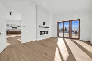 Unfurnished living room with a towering ceiling, a mountain view, and light hardwood / wood-style flooring