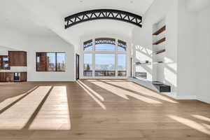 Unfurnished living room featuring a mountain view, high vaulted ceiling, wine cooler, and light hardwood / wood-style floors