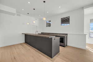 Kitchen featuring pendant lighting, beverage cooler, kitchen peninsula, and light wood-type flooring