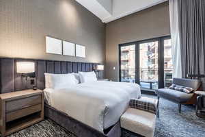 Bedroom with access to outside, carpet, and a towering ceiling