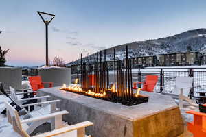 Snow covered patio featuring a mountain view and an outdoor fire pit