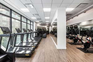 Exercise room with a paneled ceiling and hardwood / wood-style flooring