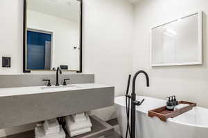 Bathroom featuring sink, a tub to relax in, and hardwood / wood-style floors