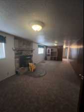 Basement with a textured ceiling, a fireplace, and carpet flooring