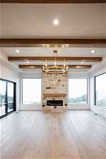 Great room featuring beamed ceiling, a notable chandelier, and light hardwood / wood-style flooring