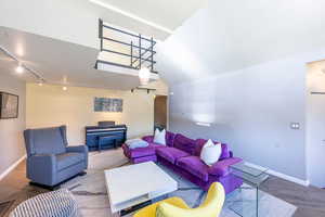 Living room featuring track lighting, hardwood / wood-style flooring, and vaulted ceiling