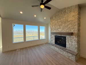 Unfurnished living room featuring ceiling fan, a fireplace, a mountain view, light hardwood / wood-style floors, and lofted ceiling