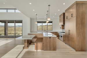 Kitchen featuring high end range, wall chimney range hood, pendant lighting, a center island with sink, and a mountain view