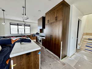 Kitchen featuring sink, hanging light fixtures, tasteful backsplash, light stone counters, and double oven range