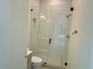 Bathroom featuring an enclosed shower, vanity, and toilet