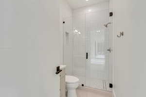 Bathroom adjacent to the office or second bedroom  featuring tile patterned flooring, vanity, a shower with shower door, and toilet