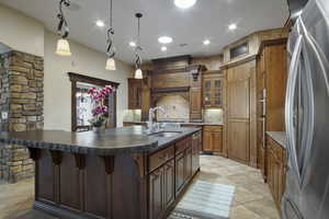 Kitchen with stainless steel appliances, decorative backsplash, pendant lighting, sink, and a kitchen island with sink