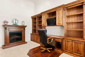 Office area featuring built in study area, a glass covered fireplace, and carpet flooring