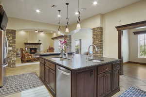 Kitchen with a center island with sink, appliances with stainless steel finishes, sink, and a fireplace