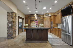 Kitchen featuring a center island with sink, sink, tasteful backsplash, appliances with stainless steel finishes, and pendant lighting