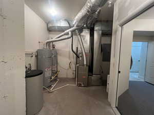 Utility room featuring strapped water heater