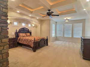 Carpeted bedroom with coffered ceiling, ceiling fan, multiple windows, and beamed ceiling