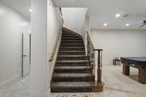 Staircase featuring ceiling fan and carpet