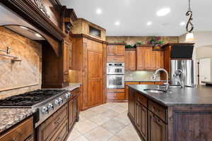 Kitchen with tasteful backsplash, appliances with stainless steel finishes, ventilation hood, recessed lighting, and light tile patterned flooring