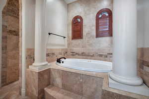 Bathroom with decorative columns, tile walls, and tiled tub