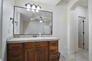 Guest private bathroom with tile flooring, a ceiling fan, vanity with extensive cabinet space, and mirror