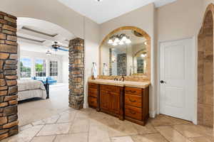 Ensuite bathroom with stone tile flooring, vanity, coffered ceiling, ceiling fan, and beam ceiling