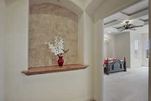 Corridor with beam ceiling, coffered ceiling, and light colored carpet