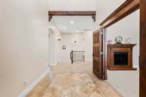 Hallway featuring inlaid floor details, recessed lighting, arched walkways, beamed ceiling, and an upstairs landing