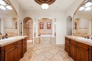 Bathroom with a garden tub, two vanities, and decorative columns