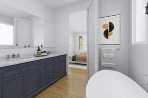 *Virtually Staged* Bathroom featuring hardwood floors, natural light, a bathtub, mirror, and his and hers large vanity