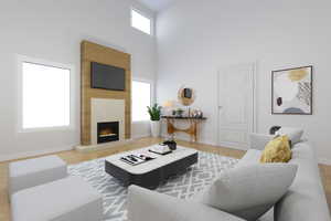 *Virtually Staged* Hardwood floored living room with a high ceiling, a fireplace, natural light, and TV