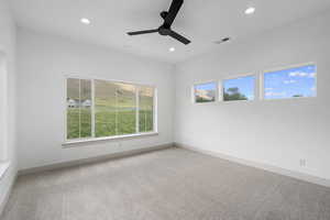 Carpeted empty room with a ceiling fan and a healthy amount of sunlight