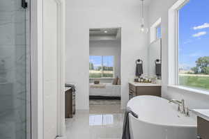 Bathroom featuring tile floors, a wealth of natural light, a bathtub, and vanity