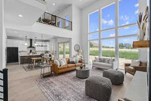 Living room featuring hardwood flooring, a high ceiling, and a breakfast bar area