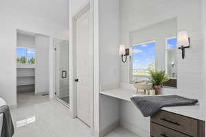 Bathroom with a wealth of natural light, tile flooring, multiple mirrors, shower with shower door, and vanity