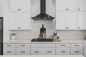 Kitchen with gas stovetop, ventilation hood, white cabinets, and light countertops