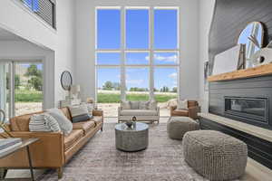 Living room featuring a fireplace, a high ceiling, and natural light