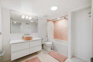 Full bathroom featuring oversized vanity, mirror, toilet, shower / tub combination, and shower curtain